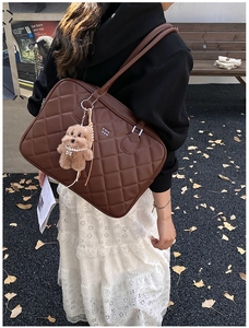 Detail of dark brown quilted tote bag with cute plush bear charm on a female model