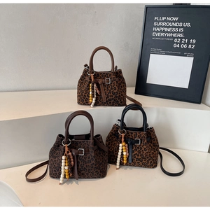 Detailed view of leopard print bucket bags with wooden bead charms and adjustable straps