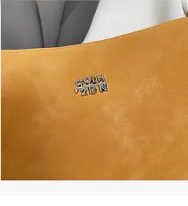 Macro detail of silver metal logo on yellow faux suede vintage bucket bag texture