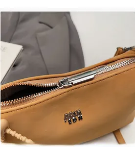 Detail of silver metal zipper and brand logo on a solid color leather tote bag