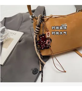 Detail of mustard yellow leather bucket bag with leopard bear charm and silver hardware