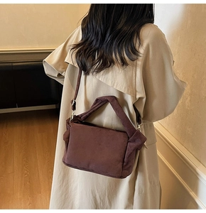 Detail of soft dark brown suede shoulder bag with adjustable strap and top handle