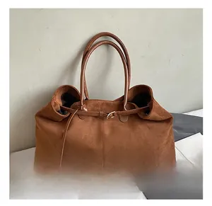 Detail of a brown suede tote bag featuring a gold buckle strap and soft vintage texture