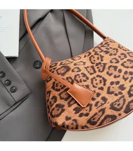 Close-up of leopard print suede underarm bag with brown leather strap on gray blazer
