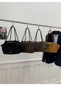 Detail of four colored suede tote bags with golden metal buckles and brand logo