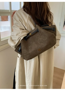 Detail of the oversized faux suede tote bag featuring black drawstrings and metal buckles