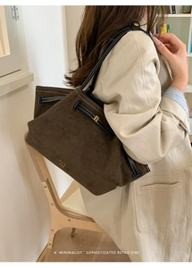Detail of dark brown suede tote bag featuring black leather drawstring and golden logo