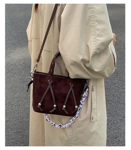 Detail of dark brown suede shoulder bag with decorative knotted tassels and silver beads