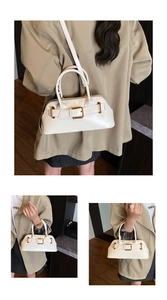 Detail view of cream faux leather handbag with gold hardware buckle and adjustable strap