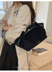 Detail of black suede tote bag featuring white contrast stitching and PAN TOR logo