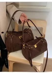 Détail de sacs Boston en daim marron de deux tailles avec garnitures dorées chic