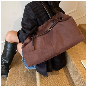 Detail of a large dark brown suede tote bag with slim leather straps and metal buckle
