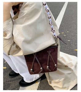 Close-up of brown suede bucket bag with cow print beaded strap and metallic details