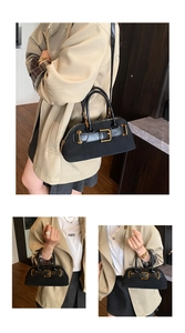 Detail view of black suede shoulder bag featuring decorative buckle and gold hardware