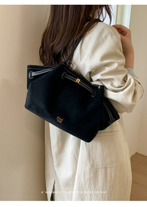 Detail of vintage black suede tote bag with white contrast stitching and gold logo