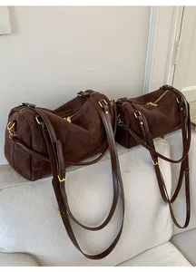 Détail des sacs Boston en daim marron foncé en deux tailles avec finitions dorées