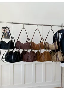 Sacs polochons minimalistes en daim aux tons terreux exposés sur des cintres en métal