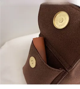 Dettaglio della borsa a mezzaluna in camoscio marrone con chiusura magnetica dorata e tasca