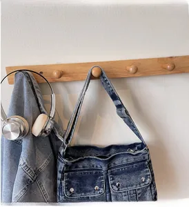 Detail of washed denim shoulder bag featuring dual front pockets with metal studs