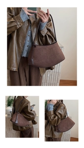 Detailed close-up of a vintage dark brown suede crescent shoulder bag with sleek leather strap