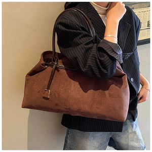 Detail view of brown suede tote bag featuring slim contrast straps and metal buckle