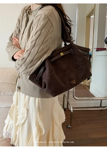 Detail of large brown suede tote bag with white stitching and gold brand logo
