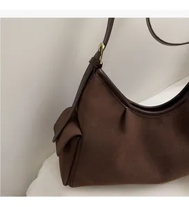 Dettaglio della borsa dumpling marrone scuro con trama in pelle scamosciata e bordi