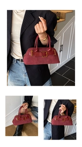 Close-up of burgundy suede shell bag featuring vintage gold buckle and smooth texture
