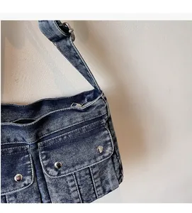 Close-up of vintage blue denim shoulder bag with metal rivets and pocket detail