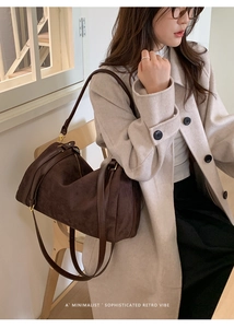 Gros plan d'un sac Boston en daim marron foncé porté avec un manteau élégant de couleur crème