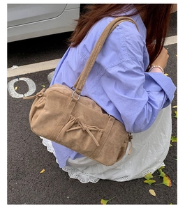 Détail du sac à bandoulière marron rétro avec plis à nœuds porté par un mannequin chic