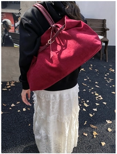 Close-up of burgundy suede tote bag with metal buckles and decorative strap detail