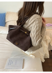 Detail of soft dark brown suede tote bag with signature brand lettering and slim strap