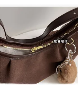 Dettaglio della cerniera dorata e della texture scamosciata marrone della borsa vintage