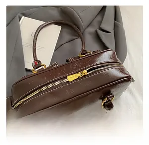 Detail view of glossy oil-waxed leather Boston bag with premium gold zipper and hardware