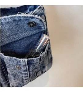 Detail of washed denim bag featuring a front snap pocket and secure zipper closure