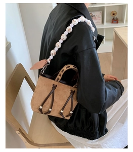 Close-up of brown suede shoulder bag with unique leopard and white beaded strap detail