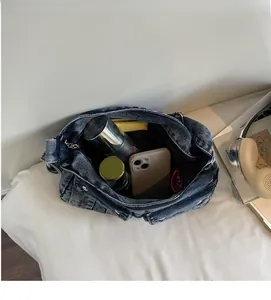 Interior view showing the large capacity of a washed denim shoulder bag for daily items