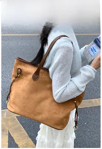 Detailed view of brown suede tote bag featuring leather handles and side drawstring details