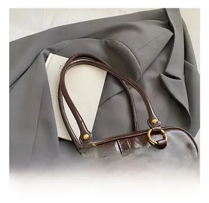 Detail of dark brown glossy handle and golden hardware on vintage style handbag