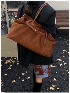 Detail of soft brown suede tote bag featuring slim decorative straps for autumn look