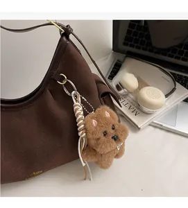 Dettaglio borsa shopper marrone scuro con ciondolo a forma di cucciolo e fibbie dorate