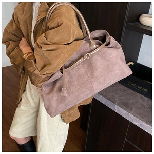 Macro detail of dusky rose suede tote bag with textured shoulder strap and decorative buckle
