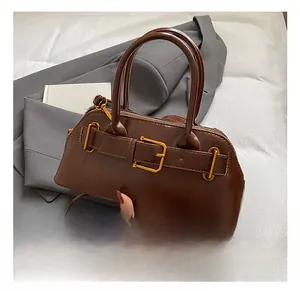 Detail showing the brown leather shell bag with gold buckle and round handles