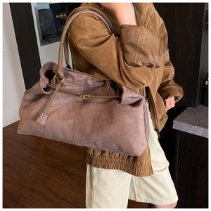 Detail view of pink suede tote bag featuring side lacing and dark leather handle
