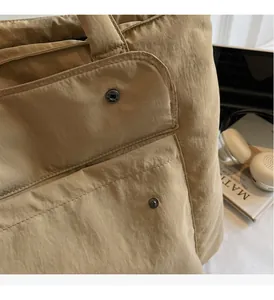 Detail der khakifarbenen Nylontasche mit strukturierter Oberfläche und Metalldruckknopf