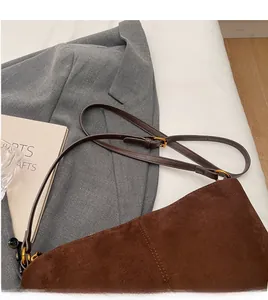 Detail of adjustable dark brown suede shoulder strap with gold-tone circular metal buckle
