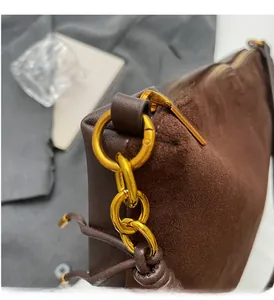 Close-up of vintage dark brown suede handbag with luxury gold hardware and braided strap