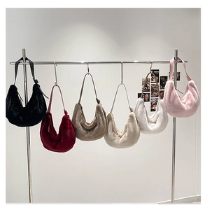Détail de sacs hobo en peluche de six couleurs suspendus à un support en inox