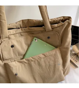 Detail der khakifarbenen Tragetasche mit Doppeltaschen und Platz für ein Tablet